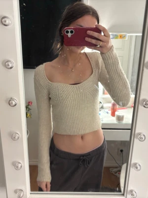 Beige cropped stickad tröja  - Trendig beige stickad tröja från Gina Tricot med croppad passform och bred, fyrkantig urringning. Tröjan har långa ärmar och ribbstickad struktur som ger en snygg siluett. 