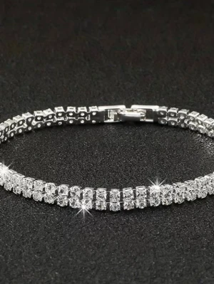 Glittrigt armband i silverfärg - Snyggt tennisarmband i silverfärg med två rader gnistrande klara stenar som ger en lyxig känsla. Armbandet har en klassisk, smal design och ett smidigt lås. Perfekt för dig som vill ha något som verkligen blänker och sticker ut.