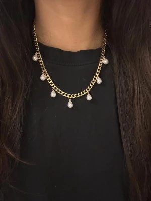 Guldpläterat 6mm bred halsband med droppformade pärlor - Elegant halsband i guldpläterat rostfritt stål – finns även i silverfärgad variant. Matchande örhängen finns i en separat annons.  Smycket är 6 mm brett och har en justerbar längd mellan 42–50cm, vilket gör att det passar perfekt oavsett stil och tillfälle.. De nickelfria och handgjorda. 