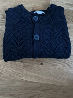 Mörkblå stickad kofta från Gina Young - Snygg svart kofta från Gina Tricot Young i storlek 146/152, men passar på mig som är ungefär 175,  med fint stickat mönster och stora knappar framtill. Koftan har rund halsringning och ribbade detaljer vid kanterna. Perfekt för lager på lager och är en basic men fin del till din outfit. Pris kan diskuteras💞✌️