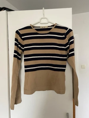 Randig långärmad topp från Flash Basic - Beige och svart långärmad topp från Flash basic. Rund halsringning och mjukt material som känns skönt mot huden.