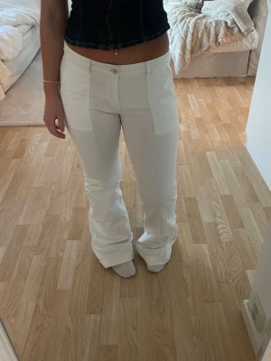 Vita utsvängda jeans med fickor - Säljer ett par vita lågmidjade utsvängda jeans stora fickor framtill. Säljer då de är långa på mig. Jeansen har en fläck bak från etiketten som jag har tagit bort då den färgade av sig, sista bilden. Köpa på plick. 