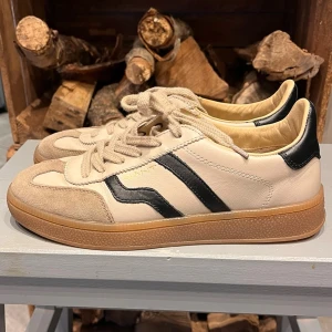 GANT  sneakers - Sneakers från GANT, modell Cuzima i off-white skinn med svarta vågiga detaljer på sidorna och beige mocka vid tån. Sparsamt använda så de är i mycket fint skick. Nypris 1800 kr. Nu 900 kr.