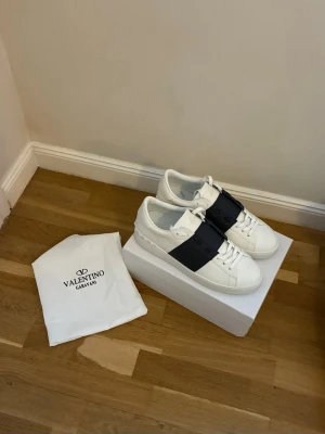 Valentino Garavani Open sneakers vit marinblå stl 44 Helt nya vit/svart - Säljer ett par Valentino Garavani Open sneakers. Kommer med originalpåse och box. Perfekta för dig som vill ha en clean men lyxig look. Stl 46.