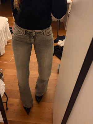 Grå bootcut jeans med låg midja - Snygga grå bootcut jeans med låg midja och klassisk femficksdesign. Jeansen har en lätt tvättad look och raka ben som går ut lite nedtill. Perfekta att styla med sneakers eller boots för en trendig vibe.