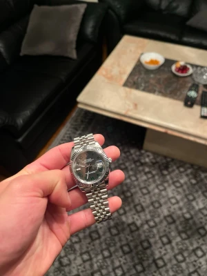 Rol*x  herrklocka 41:a - Säljer en stilren Rol Datejust herrklocka i wimbeldon med klassisk länkarmband och mörk urtavla. Klockan har tydliga index, datumvisning och en räfflad bezel. Perfekt för dig som vill ha en ikonisk accessoar med tidlös design.