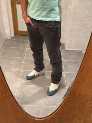 Mörkgråa jeans från Replay.  - Säljer ett par mörkgråa jeans från Replay med modellen anbass. Storleken är W34. Jeansen har raka ben och är tillverkade i ett mjukt denim-material som ger en skön känsla. Perfekta för dig som gillar en enkel och stilren look.