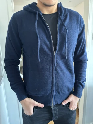 Mörkblå Merinoull Hoodie med dragkedja  i storlek S - Tjena, säljer denna as feta mörkblå merinoull hoodie med dragkedja i storlek S. Perfekt för sommaren. Inga skavanker eller några sorters skador på den alls. Bara att höra av sig om det är någonting som undras!