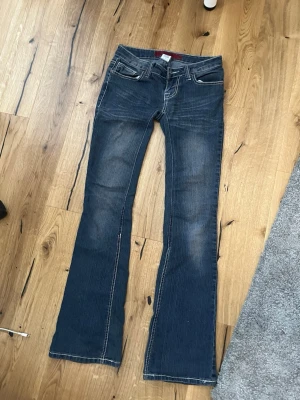 Mörkblå bootcut jeans med broderi - coola jeans som är vintage! midje mått:33cm benbrädd: 20cm längd:94cm