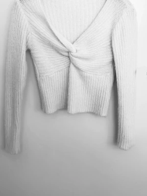 Vit twistad stickad tröja🤍 - Trendig vit stickad tröja med twistad detalj framtill och djup v-ringning. Tröjan har ribbstickad struktur, långa ärmar och croppad passform. Perfekt för lager på lager och en snygg vardagslook.