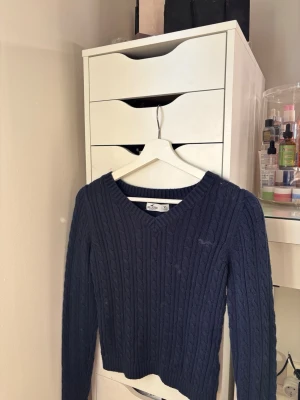 Hollister - Mörkblå kabelstickad tröja från Hollister med V-ringning och långa ärmar. 