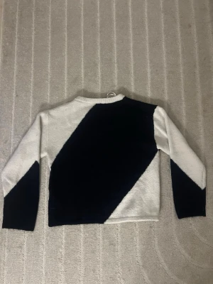 Stickad tröja med svartvit diagonal design - Säljer en stickad tröja med diagonal färgblock-design i svart/mörkblått och vitt, från Gina-Tricot. Storlek 158-164