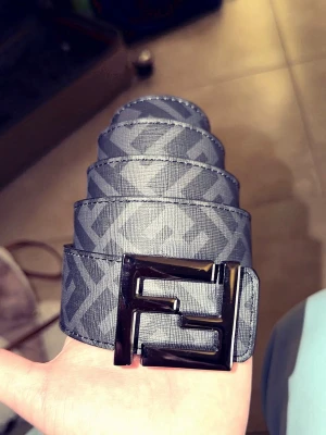 Grått Fendi bälte med FF-logga - Snyggt grått bälte från Fendi med ikoniskt FF-mönster och stor metallspänne i svart. Bältet har en modern look och passar perfekt till jeans eller byxor för att lyfta din outfit.