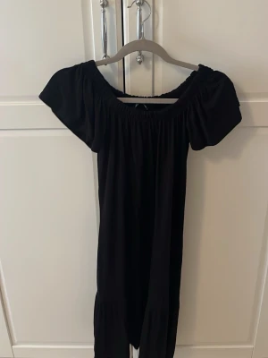 Svart gina volang klänning  - En volang klänning som går och ha off shoulder eller vanligt i storlek xs som är perfekt över bikini på stranden. Nästan oanvänd.