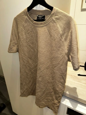 Beige ribbad t-shirt från Bershka - Säljer en beige ribbad t-shirt från Bershka i storlek L men passar också M. T-shirten har korta ärmar och en regular fit passform. Materialet är mjukt och strukturerat, vilket ger en skön känsla och en stilren look. Perfekt till jeans eller shorts! Skriv över det minsta lilla eller över den minsta funderingen!🔥🔥