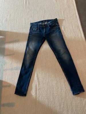 Mörkblå slim fit jeans från Lee - Säljer ett par mörkblå slim fit  replay jeans  med snygga slitningar och klassisk femficksmodell. Jeansen har en smal passform och är tillverkade i stretchigt denimtyg för extra komfort. Perfekta till en avslappnad streetstyle-look.  Storlek 32 