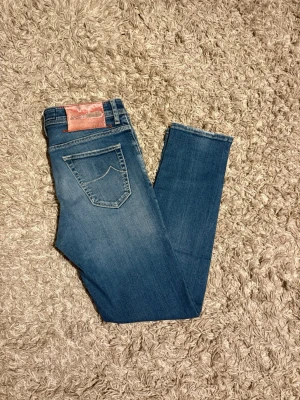 Jacob Cohën jeans  - Snygga blå skinny jeans från  Jacob Cohën med klassisk femficksmodell och knäppning med silverfärgade knappar. Jeansen har en lätt tvättad look och är tillverkade i stretchigt denim för skön passform. Perfekta till en avslappnad stil.