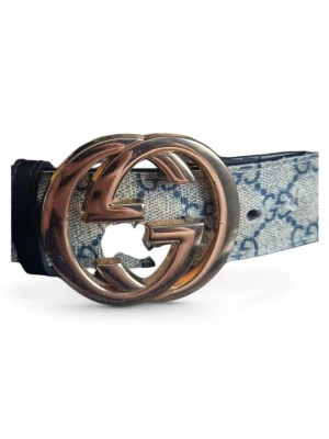 Gucci GG bälte med monogramspänne - Snyggt bälte från Gucci med klassiskt GG-monogram i blått på beige bakgrund och stort guldfärgat GG-spänne. Bältet har en stilren design och är perfekt för att lyfta vilken outfit som helst. Materialet är skinn med canvasdetaljer.