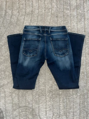 Replay Anbass jeans - Mörkblåa Replay Anbass jeans med snygg ljus fade med skön och slim passform. Midja 37cm, längd 108cm. Obs vänstersida vid fickad så är de små vita fläckar - se bild. Längdstorleken saknas, jag skulle bedöma till L34 men utgå efter mått. JAG SKICKAR EJ FLER BILDER NÄR JAG BÄR JEANSEN! för bättre inblick i passformen rekommenderar jag att googla på modellnamnet. För storleksguide kolla måtten noggrant då jeansen alltid kan vara uppsydda heller krympta och jag ej tar emot returer :) 1,70