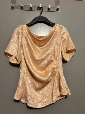 Champagnefärgad topp Shein - Snygg champagnefärgad topp från Shein med korta ärmar. Toppen har en draperad halsringning och lätt utsvängd passform. Perfekt för dig som vill sticka ut lite extra.