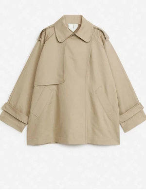 Beige kort trenchcoat med bred krage - Så snygg kort trenchcoat från ARKET i XS (oversized). Enbart använd ett par gånger så i kanonskick! Perfekta vårjackan! Nypris: nästan 2000 kr