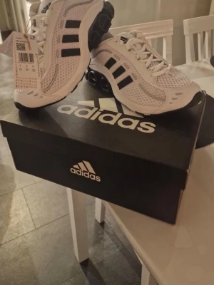 Vita Adidas sneakers med svarta detaljer - Snygga vita Adidas sneakers med svarta ränder och cool svart sula. Helt nya, de har aldrig används. Jag postar snabbt vid snabbt köp!! 💞