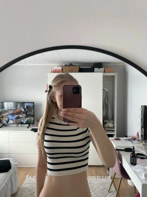 Randig croppad topp från Zara - Säljer en croppad topp från Zara med marinblå och vita ränder. Toppen är ärmlös och har en ribbad struktur med rund halsringning. Perfekt för dig som gillar en clean och stilren look.