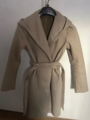 Zara kappa med luva - Beige lite längre kappa med luva. Den är väl använd och är smått nopprig runt om, men det går att få bort.