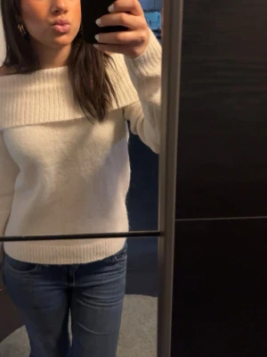 Vit offshoulder stickad tröja - Superfin vit stickad tröja med bred offshoulder-krage. Tröjan har lång ärm och ribbade muddar vid ärmslut och nederkant. Perfekt för dig som vill ha en mysig men ändå snygg look. Storlek 170  så skulle säga passar xs-s!