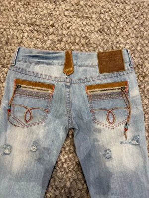 Ljusblå slitna jeans från Alcott -  Coola och unika jeans från Alcott med slitningar och andra speciella detaljer. De är i jätte fint skick. Låg midja och raka ben. Skriv vid frågor eller mått💕