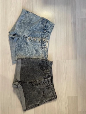 Två par denimshorts med högmidja - Två par jeansshorts i stretchigt material från NewYorker i storlek M. Ena paret är ljusblått och andra paret är grå/ svarta. Dom båda är högmidjade och endast använda ett fåtal gånger.                                    (dock har limmet bakom märkeslapparna börjat släppa lite men annars inga konstigheter.)                            Hör gärna av dig om du har någon fråga!