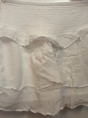 Vit volangkjol från Gina Tricot - Supersöt vit kortkjol från Gina Tricot med volangdetaljer och smock i midjan. Säljer för att jag inte har användning för den längre!💞