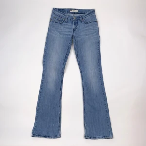 Lågmidjade bootcut jeans från Levis  - Ett par lågmidjade klassiska ljusblå Levi's jeans med bootcut passform. Jeansen har fem fickor, knappgylf och snygga sömdetaljer på bakfickorna. Modell 524.  Strl: W24 L32, lite stretch.  