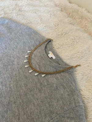 Guldfärgat halsband med pärldroppar - Snyggt halsband i guldfärgad rostfritt med kedja och hängande droppformade pärlor. Perfekt för att ge outfiten lite extra bling och stil. Passar dig som gillar trendiga accessoarer med en elegant touch.