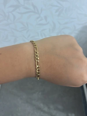 Guldfärgat kedjearmband - Stilrent guldfärgat armband med klassisk kedjedesign. Armbandet har ovala länkar och ett smidigt lås som gör det enkelt att ta på och av. Perfekt för dig som gillar minimalistiska accessoarer med en touch av guld. Passar till många olika stilar.