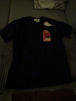 Svart Casablanca t-shirt med tryck - Snygg svart t-shirt från Casablanca med stort grafiskt tryck i rött och vitt på ryggen och mindre tryck framtill. Klassisk passform och rund hals. Perfekt för dig som gillar streetwear och vill sticka ut med en unik design.