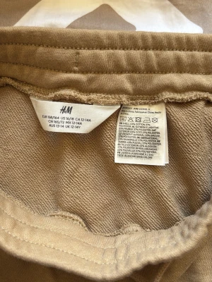 Beige kjol med fickor från H&M - Säljer en beige kjol från H&M i mjuk bomullsblandning. Kjolen har en rak passform, resår i midjan och praktiska fickor på sidorna. Perfekt för en avslappnad och trendig look.