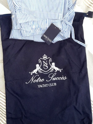  Notre Succès Randig pyjamasbyxa - Ej använd - nya Blåvita loungewear-byxor från Notre Succès med klassiskt smalrandigt mönster och dragsko i midjan. Tillverkade i mjukt tyg, perfekta för chill utomlands-hemma . Levereras med snygg tygpåse med broderad logga.