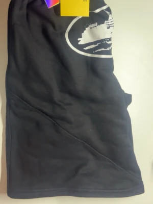 Svarta shorts från corteiz  - Svarta shorts från Midlunk med vit tryckt logga framtill. Klassisk passform med elastisk midja och mjukt material som känns skönt mot huden. Perfekta för en avslappnad stil under varma dagar.