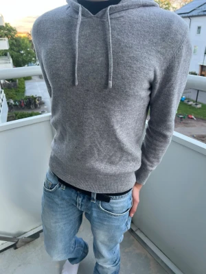 Sayless Kashmir hoodie med armbågslappar XS - Sayless kashmir hoodie med armbågslappar. Hoodien fick slitningar i armbågarna så jag fick den proffesionellt lagad med mörkgråa armbågslappar i ull. Passar perfekt för en sval sommardag. Tröjan är i mjukt stickat material och har ribbade muddar vid ärmslut och nederkant.  XS