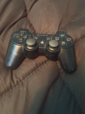 Sony DualShock 3 trådlös handkontroll - Säljer en svart Sony DualShock 3 trådlös handkontroll till PlayStation 3. Klassisk design med två analoga spakar, styrkors och de ikoniska PlayStation-knapparna i färg. Tillverkad i plast med skön form för gaming.