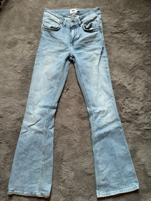 Ljusblå bootcut jeans från 157 - Säljer ett par ljusblå bootcut jeans från 157 med klassisk femficksdesign och utsvängda ben. Jeansen har normal midja och är gjorda i mjuk denim. Perfekta för dig som gillar retrovibbar och en avslappnad look. De är i längden short.