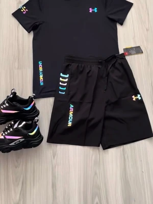 Under Armour svart reflex  - Säljer ett svart träningsset från Under Armour med t-shirt och shorts. Båda plaggen har logotypen i regnbågsfärger och texten UNDER ARMOUR på sidan. Materialet är lätt och andas, perfekt för gym eller löpning. Eller sommaren en fin outfit 
