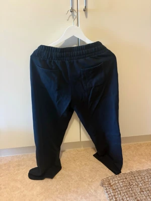Svarta mjukisbyxor med dragsko - Säljer ett par svarta mjukisbyxor med resår i midjan och dragsko. Byxorna har två fickor fram och två bakfickor. Sköna och avslappnade med rak passform, perfekta för chill dagar. Materialet känns mjukt och bekvämt.