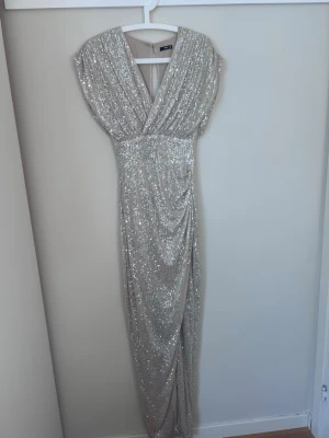Glittrig balklänning  - Superfin balklänning ifrån Asos! Jag är 174 cm och den gick hela vägen ner till marken för mig och den har lite stretch i materialet! Bara använt en gång så den är fortfarande i väldigt bra skick!                                       Nypris: 1250kr