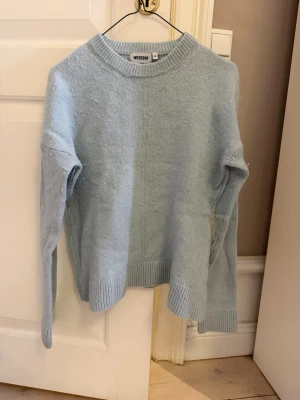 Ljusblå stickad tröja från Weekday - Mysig ljusblå stickad tröja från Weekday med rund halsringning och ribbade muddar vid ärmslut och nederkant. Materialet känns mjukt och passar till många olika stilar. 