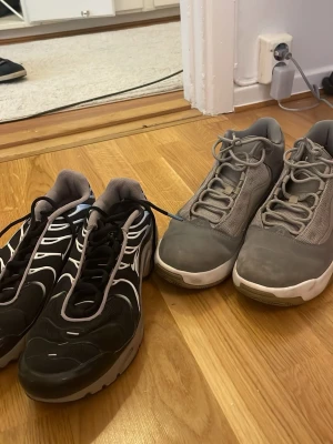Två par sneakers i svart och grått - Säljer två par sneakers, ett par i svart med vita detaljer och ett par i helgrått med mesh och mockaliknande material. Båda har klassisk låg profil och snörning. Perfekta för dig som vill ha stilrena och bekväma skor till vardags.