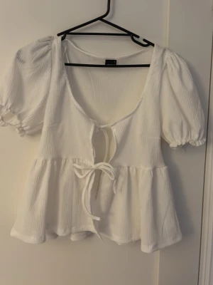 Vit blus med puffärm och knyt - Söt vit blus med puffärmar och två knyt framtill från Gina tricot aldrig använts 