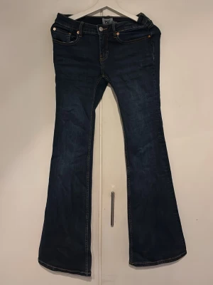 Mörkblå bootcut jeans 157 - Mörkblå bootcut jeans från 157 med klassisk femficksdesign och kontrastsömmar. Jeansen har utsvängda ben och är tillverkade i denim med lätt stretch. Perfekta för dig som gillar en retroinspirerad look.
