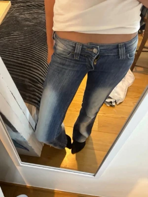 Kvarg jeans - Snygga blå bootcut jeans med ljusa slitningar framtill och klassisk femficksdesign. Jeansen har låg midja och dragkedja med knapp. Perfekta för en avslappnad och trendig look.